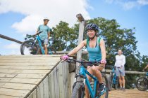Smiling young woman mountain biking at obstacle course — Stock Photo
