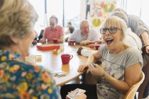 Щаслива старша жінка грає у карти з другом у громадському центрі — стокове фото