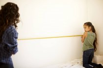 Mother and daughter measuring wall for project — Stock Photo