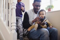 Father putting shoes on baby son on stairs — Stock Photo