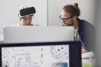 Programadores informáticos enfocados programando gafas de simulador de realidad virtual en la computadora en la oficina - foto de stock