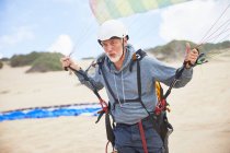 Сосредоточенный взрослый параплан с оборудованием и парашютом на пляже — стоковое фото