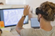 Computer programmer testing virtual reality simulator glasses at computer in office — Stock Photo