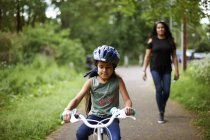 Мать смотрит дочь велосипед езда по тропинке — стоковое фото