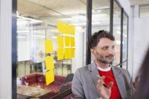 Creative businessman brainstorming with adhesive notes in office — Stock Photo