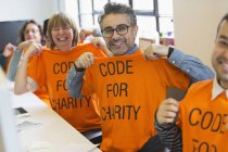 Retrato confiado hackers en camisetas codificación para caridad en hackathon - foto de stock
