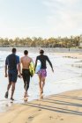 Чоловіки-серфери, що ходять з дошками для серфінгу на сонячному океані — стокове фото