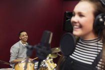 Músicos adolescentes sorridentes gravando música, assinando e tocando bateria na cabine de som — Fotografia de Stock