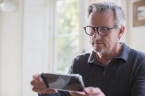 Орієнтований зрілий чоловік використовує смартфон в сучасному будинку — стокове фото