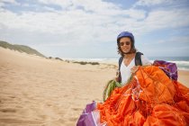 Parapente masculino sonriente con paracaídas en la playa - foto de stock