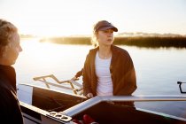 Focused female rower lifting scull at sunrise lakeside — Stock Photo