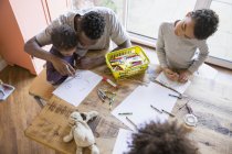 Pai africano e crianças colorir à mesa — Fotografia de Stock