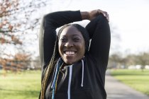 Retrato confiante feminino corredor esticando braços no parque — Fotografia de Stock
