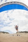 Gleitschirmfliegerin mit Fallschirm hebt am Strand ab — Stockfoto