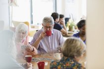 Senioren spielen und trinken Tee am Tisch im Gemeindezentrum — Stockfoto