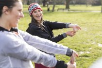 Female runners stretching wrists in park — Stock Photo