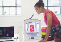 Женщина-дизайнер смотрит 3D-принтер — стоковое фото