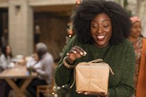Neugierige, begeisterte junge Frau öffnet Weihnachtsgeschenk — Stockfoto