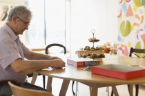 Senior man assembling jigsaw puzzle at table in community center — Stock Photo
