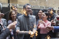 Friends celebrating birthday with cake and sparklers — Stock Photo