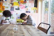 Focused brother and sister coloring at dining table — Stock Photo