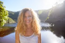 Portrait jeune femme souriante et confiante au lac ensoleillé d'été — Photo de stock