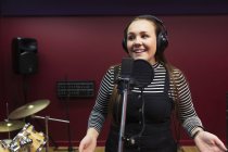 Уверенная девушка-подросток, записывающая музыку, поющая в звукозаписывающей кабинке — стоковое фото