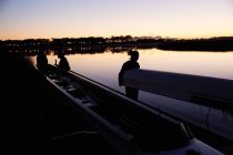 Female rowing team carrying scull at sunrise lake — Stock Photo