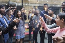 Friends celebrating with sparklers at party — Stock Photo
