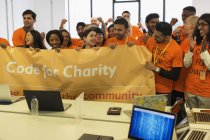 Hackers with banner cheering, coding for charity at hackathon — Stock Photo
