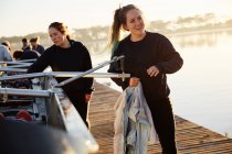 Smiling female rower preparing scull on sunny lakeside dock — Stock Photo