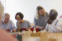 Ehrenamtliche im Gespräch mit Senioren bei Tischspielen im Gemeindezentrum — Stockfoto