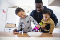Padre afroamericano jugando con niños en casa - foto de stock