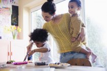 Mãe ajudando a filha da criança cortando waffles café da manhã — Fotografia de Stock