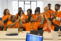 Entusiastas hackers celebrando, codificando para caridad en hackathon - foto de stock