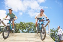 Focused men mountain biking on obstacle course ramp — Stock Photo