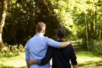 Ласковая гей-пара обнимается, гуляет в солнечном парке — стоковое фото