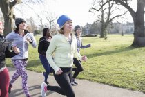 Lächelnde Läuferinnen beim Laufen im sonnigen Park — Stockfoto