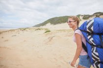 Parapendio femminile sorridente con zaino paracadute sulla spiaggia — Foto stock