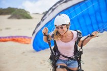 Smiling female paraglider with parachute on beach — Stock Photo