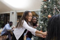 Glückliches Mädchen schmückt Weihnachtsbaum mit Familie — Stockfoto