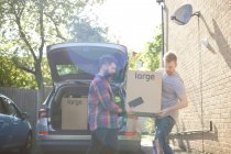 Male gay couple unloading moving boxes from car — Stock Photo