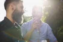 Hombre gay pareja bebiendo vino y hablando - foto de stock
