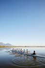Female rowers rowing scull on tranquil lake under blue sky — Stock Photo