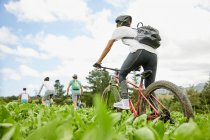 Friends mountain biking in rural field — Stock Photo