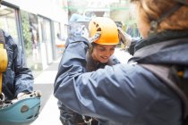 Femme aidant ami avec casque tyrolienne — Photo de stock
