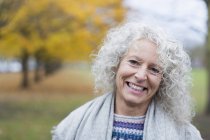 Retrato sorrindo mulher sênior no parque de outono — Fotografia de Stock