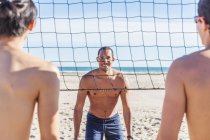 Retrato homem confiante jogando vôlei de praia na praia ensolarada — Fotografia de Stock