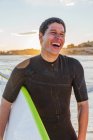 Laughing male surfer with surfboard on beach — Stock Photo