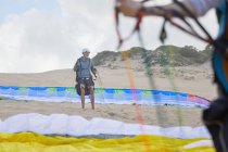 Male paraglider with parachute on beach — Stock Photo